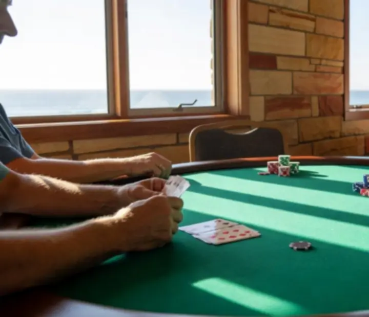 Poker table with cards, chips and people gathered in a bright restaurant